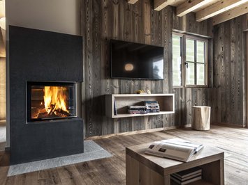 Chalet with a sauna and so much more: Kessler’s Modern living room with wood paneling, fireplace and wall-mounted TV