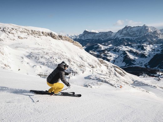 Agriturismo a Bressanone: vacanze invernali Sciatore scende su pista battuta in paesaggio montano innevato