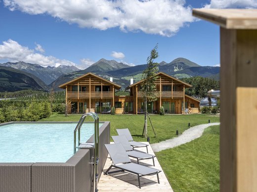 Chalet with a sauna and so much more: Kessler’s Wooden houses with pool and lounge chairs in front of mountains under blue sky
