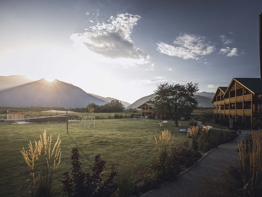 The hosts of your chalets near Brixen Sunrise over a sports field and wooden houses in a mountainous landscape