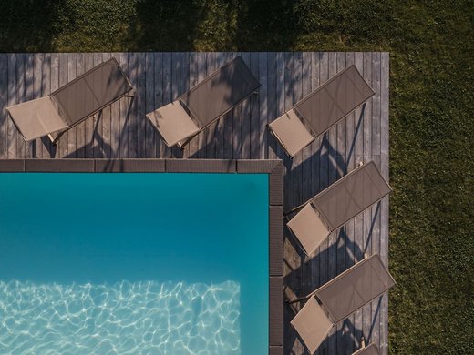 Chalet in Südtirol mit Sauna gesucht? Drohnenansicht eines Pools mit Liegestühlen und Grasflächen