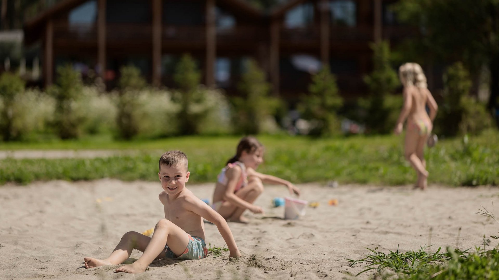 Für Familien Kinder spielen im Sand vor Holzhäusern an einem sonnigen Tag