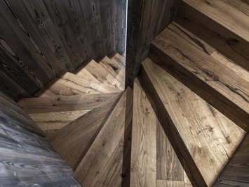 Chalet with a sauna and so much more: Kessler’s Wooden spiral staircase with dark walls viewed from above