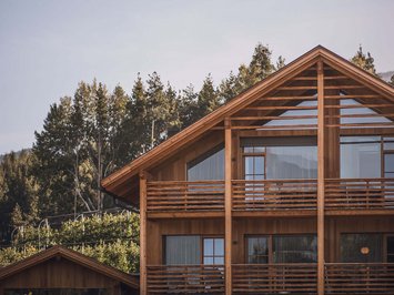 Vacanze in fattoria? Kessler’s Mountain Lodge! Casa moderna in legno con grandi finestre e balconi davanti a una foresta