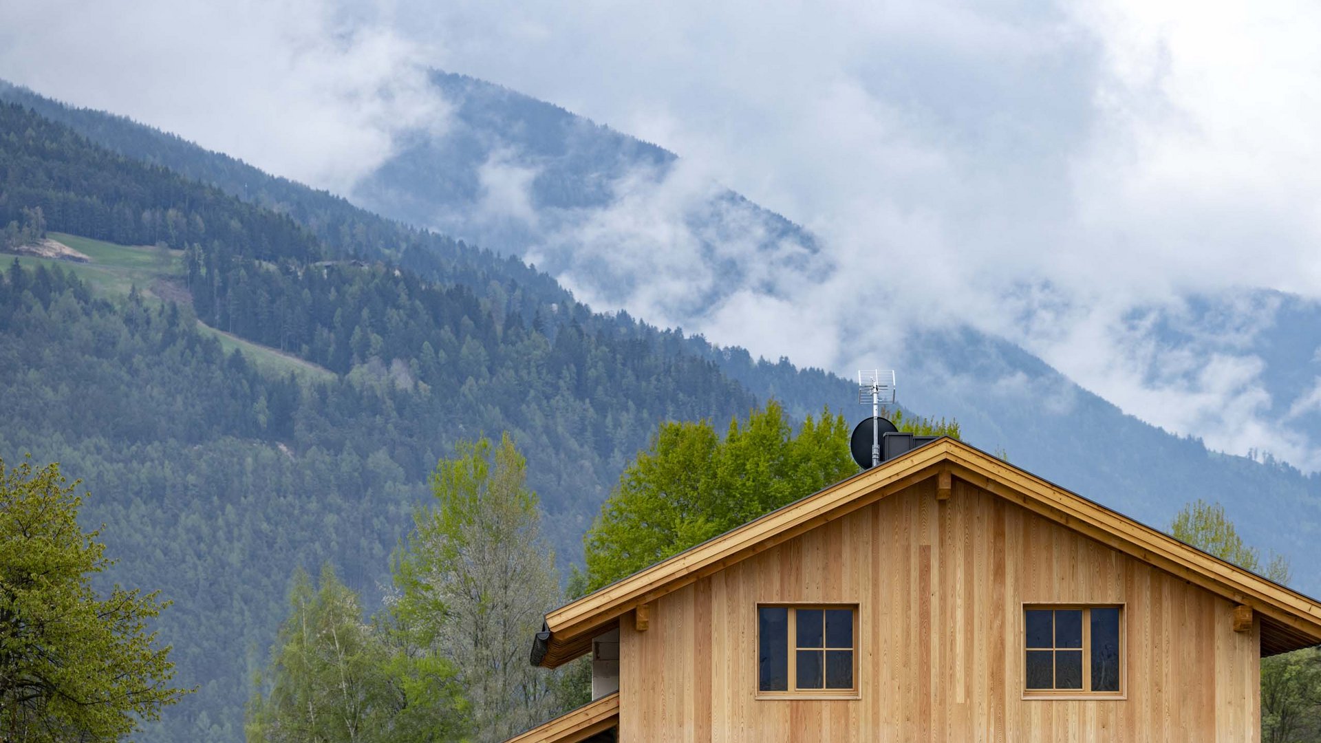 Chalet with a sauna and so much more: Kessler’s Wooden house with forested mountains and cloudy sky