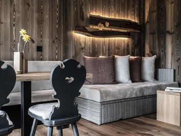 Vacanze in fattoria? Kessler’s Mountain Lodge! Angolo accogliente con pareti in legno, divano, sedie e illuminazione decorativa a parete