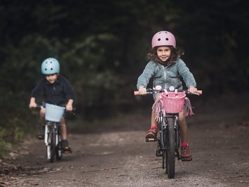 Ferienwohnung in Natz mit dem gewissen Etwas Zwei Kinder fahren mit Fahrradhelmen auf einem Waldweg Fahrrad