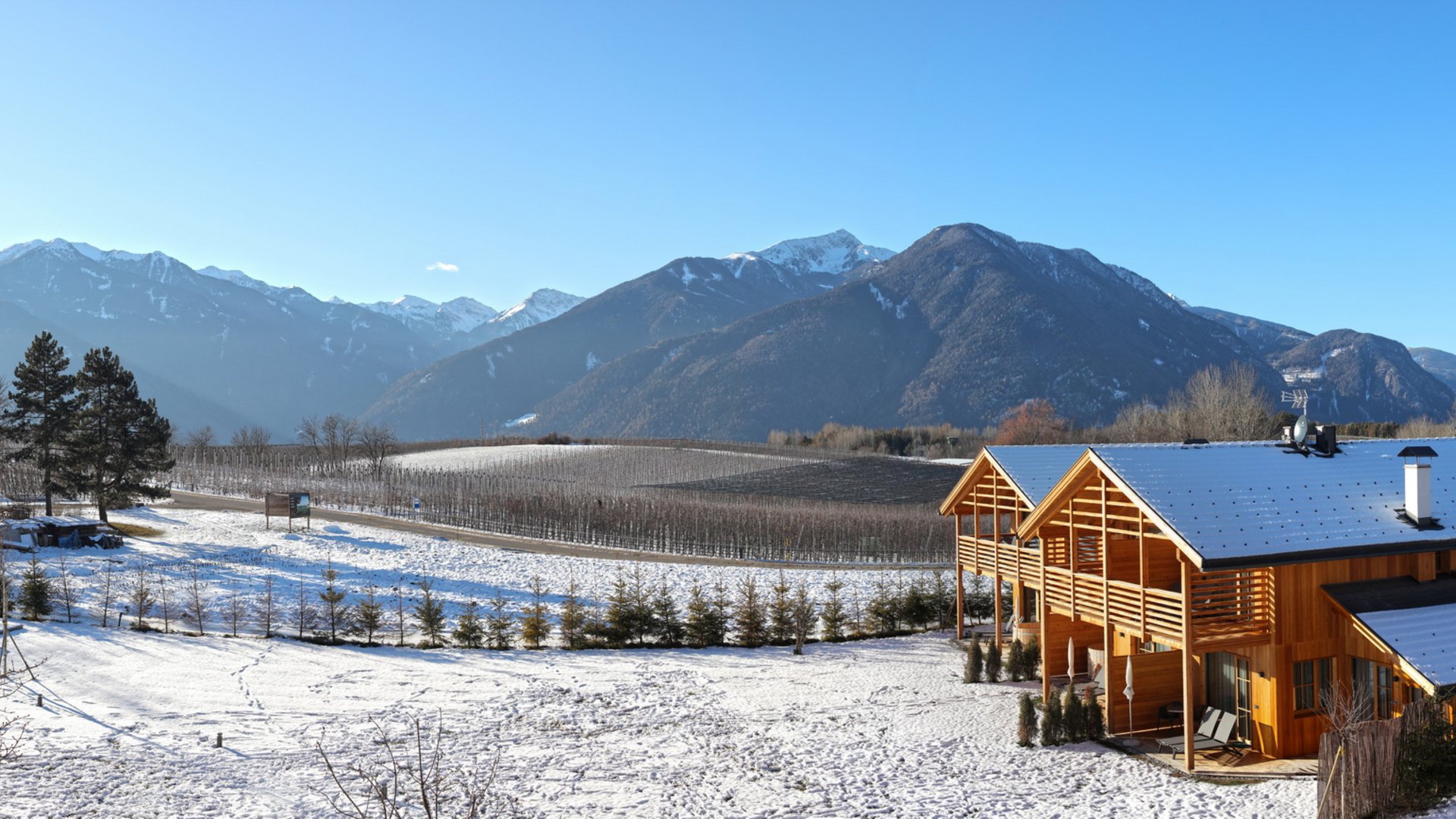 Ferienwohnung in Natz mit dem gewissen Etwas Holzhaus im Schnee vor Berglandschaft unter klarem blauen Himmel