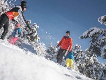 Ferienwohnung in Natz mit dem gewissen Etwas Familie spielt im Schnee an einem sonnigen Wintertag im Wald
