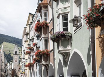 Urlaub mit Hund in Südtirol: Kessler’s! Bunte Häuserfassaden mit Blumenbalkonen in einer malerischen europäischen Stadt