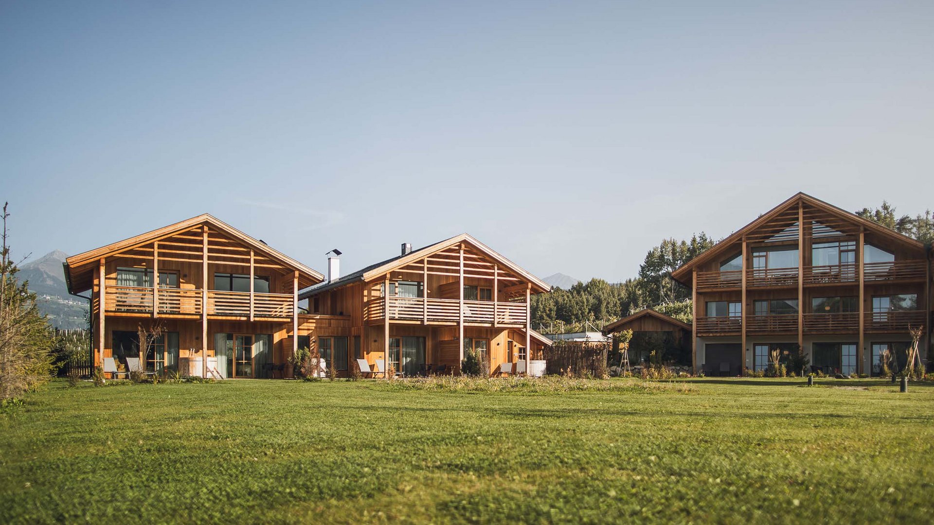 Ferienwohnung in Natz mit dem gewissen Etwas Drei moderne Holzhäuser mit großen Balkonen vor großem grünen Rasen