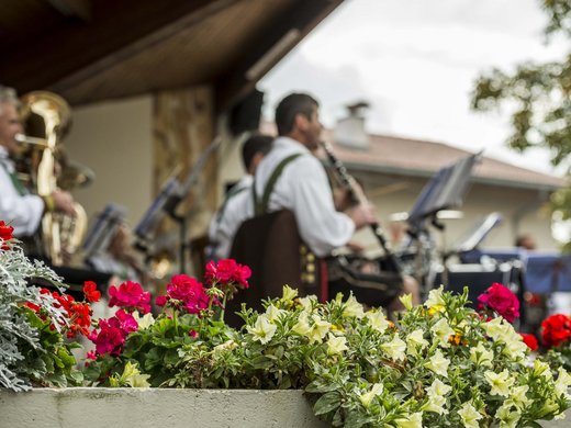 Summernacht Feschtl Blumen im Vordergrund, traditionelle Musiker im Hintergrund beim Spielen