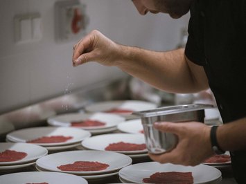 Il ristorante del Kessler: soul-food in stile fresco e sbarazzino Cuoco cosparge fette di carne cruda su piatti in cucina con sale