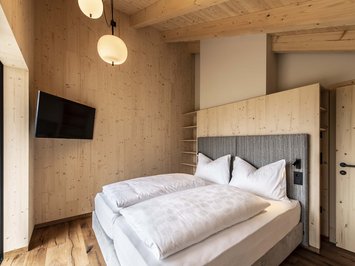 Chalet with a sauna and so much more: Kessler’s Bedroom with double bed, wooden walls, and wall-mounted TV