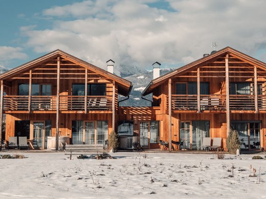 Chalet mit Sauna und noch mehr: Kessler’s Zwei Holzhäuser mit Balkonen vor einer verschneiten Bergkulisse