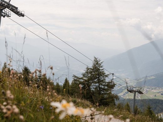Brixen Südtirol Card – das Wichtigste inklusive Zeiträumen Seilbahn über grünem Berg mit Alpen im Hintergrund