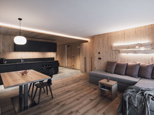 FAQ Modern living kitchen with wooden walls, black kitchen unit, and grey sofa