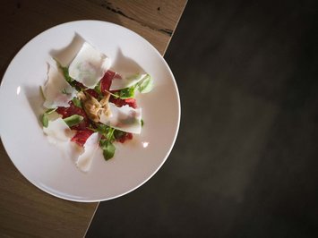 Il ristorante del Kessler: soul-food in stile fresco e sbarazzino Carpaccio di manzo con rucola, parmigiano e noci su piatto bianco