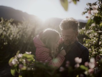 Holiday with a dog in South Tyrol: Kessler’s! Grandfather and granddaughter in blooming garden in sunlight