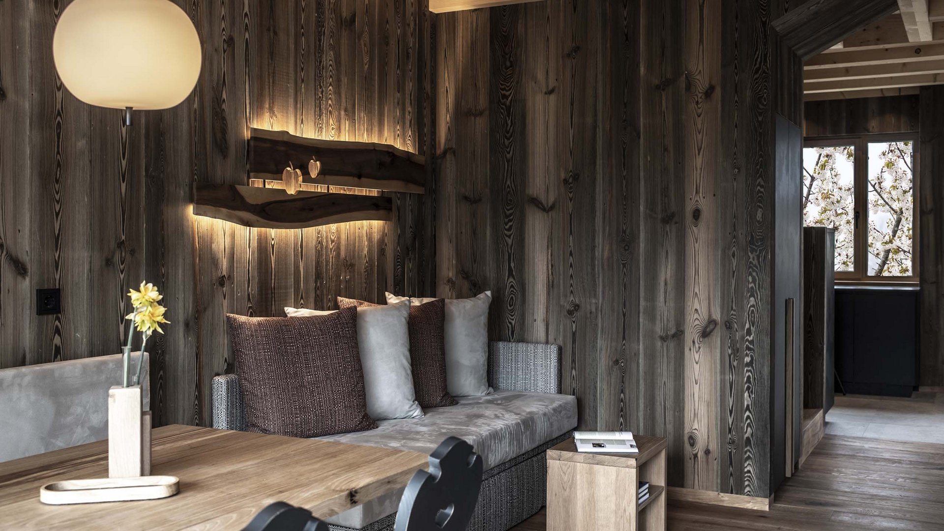 Chalet with a sauna and so much more: Kessler’s Cozy dining area with wooden table, sofa, and decorative wall lighting