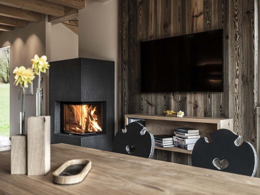 Vacanze in fattoria? Kessler’s Mountain Lodge! Soggiorno accogliente con camino moderno e tavolo in legno con fiori