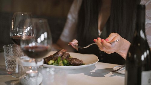 “Premium Terrasse” apartment Person eating steak with Brussels sprouts in elegant restaurant with red wine.