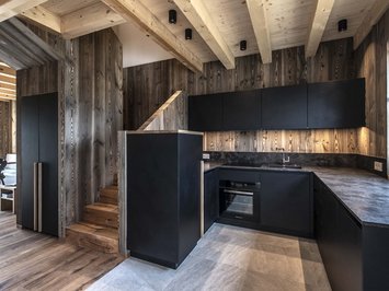 Chalet with a sauna and so much more: Kessler’s Modern kitchen with black cabinets and wooden paneling