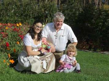 The hosts of your chalets near Brixen Family with mother, father, and two children in garden on a sunny day