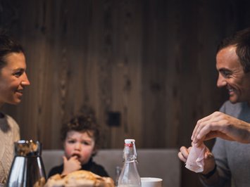 Für Familien Famiglia che fa colazione insieme a un tavolo di legno in un ambiente accogliente