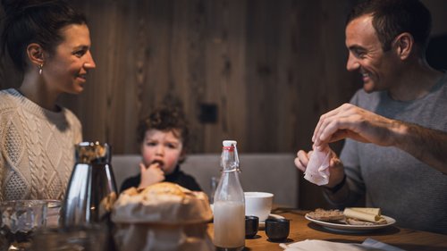 Alloggio a Bressanone: i padroni di casa Famiglia che fa colazione insieme a un tavolo di legno in un ambiente accogliente