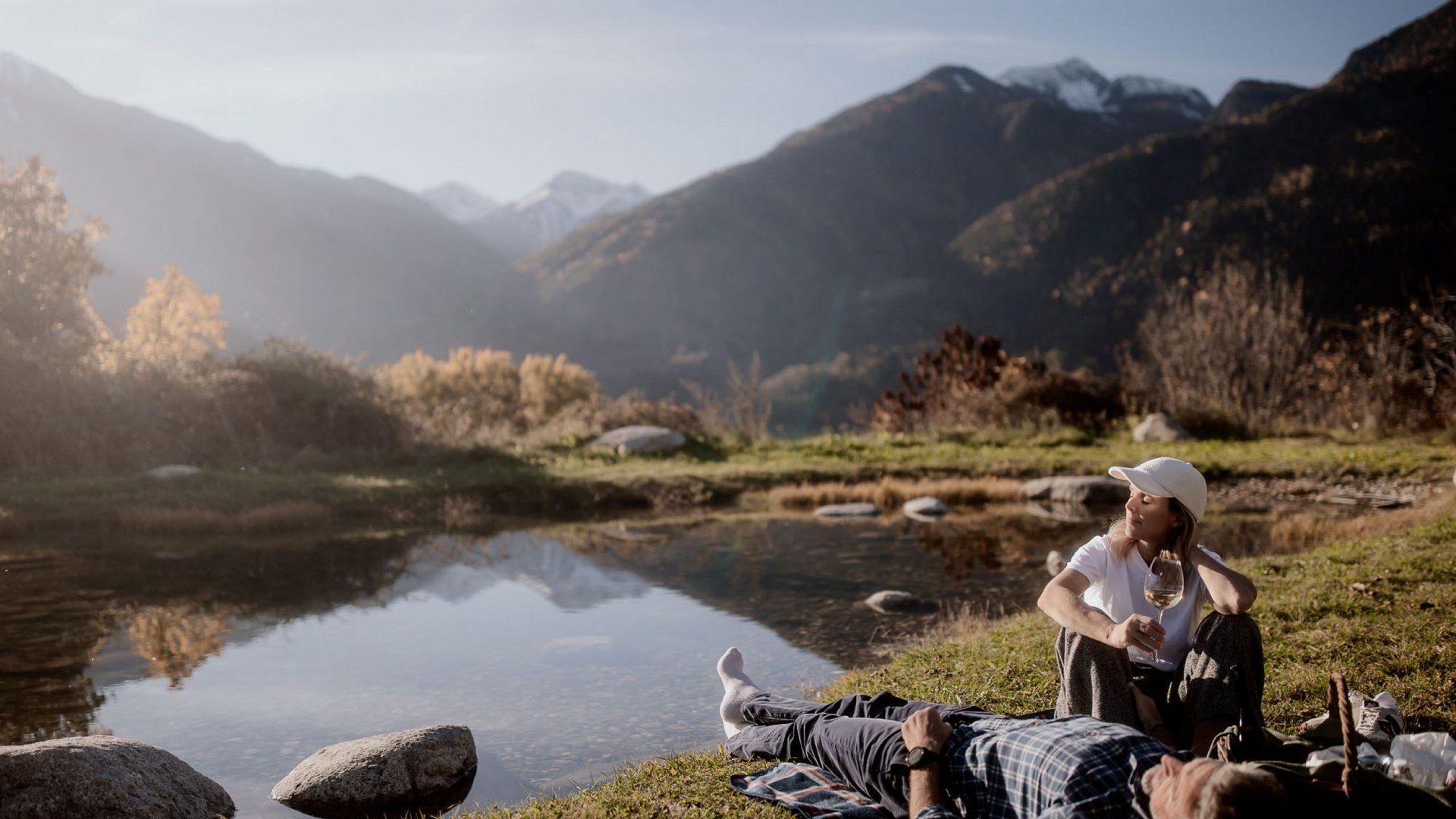 Urlaub in Natz-Schabs? Kessler’s Mountain Lodge! Paar entspannt am See im Gebirge mit einem Glas Wein