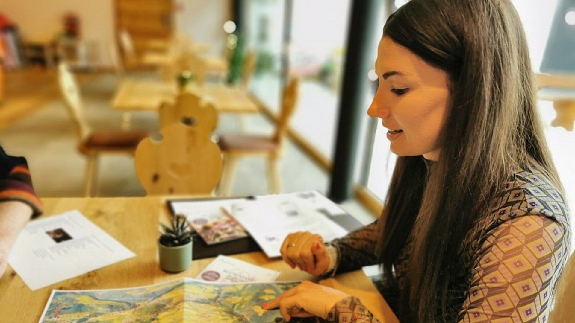 Karriere bei Kessler's Frau zeigt auf eine Landkarte auf einem Holztisch in einem Café
