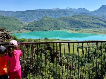 Ferienwohnung in Natz mit dem gewissen Etwas Zwei Kinder schauen über Geländer auf See und Berge unter klarem Himmel