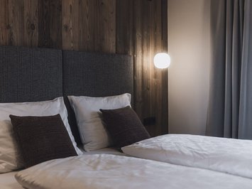 Chalet with a sauna and so much more: Kessler’s Cozy bed with white pillows against wooden panel wall and curtains