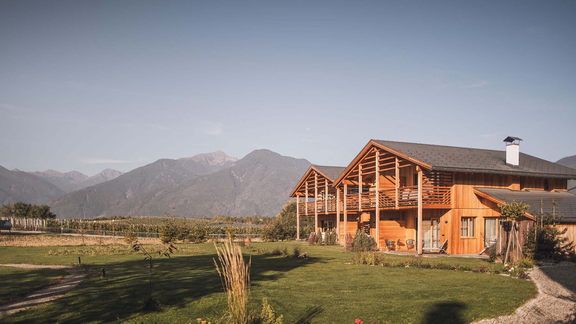 Chalet with a sauna and so much more: Kessler’s Wooden building with balcony on green lawn in front of mountains under clear sky