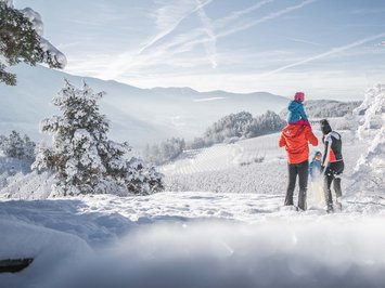 Agriturismo a Bressanone: vacanze invernali Famiglia che gode di un paesaggio invernale innevato con montagne