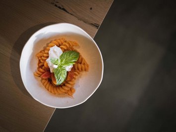 Il ristorante del Kessler: soul-food in stile fresco e sbarazzino Pasta con salsa di pomodoro, burrata e basilico su piatto bianco