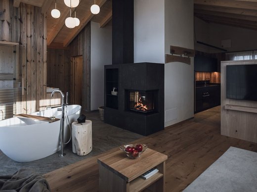 FAQ Modern living room with wooden ceiling, fireplace, standalone bathtub, and TV