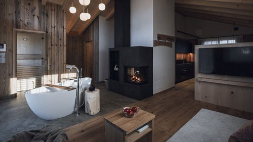 Frisch, regional und so gut. Modernes Wohnzimmer mit Holzdecke, Kamin, freistehender Badewanne und Fernseher