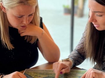 Karriere bei Kessler's Zwei Frauen studieren eine Landkarte am Tisch mit einer Platte Wurst und Käse