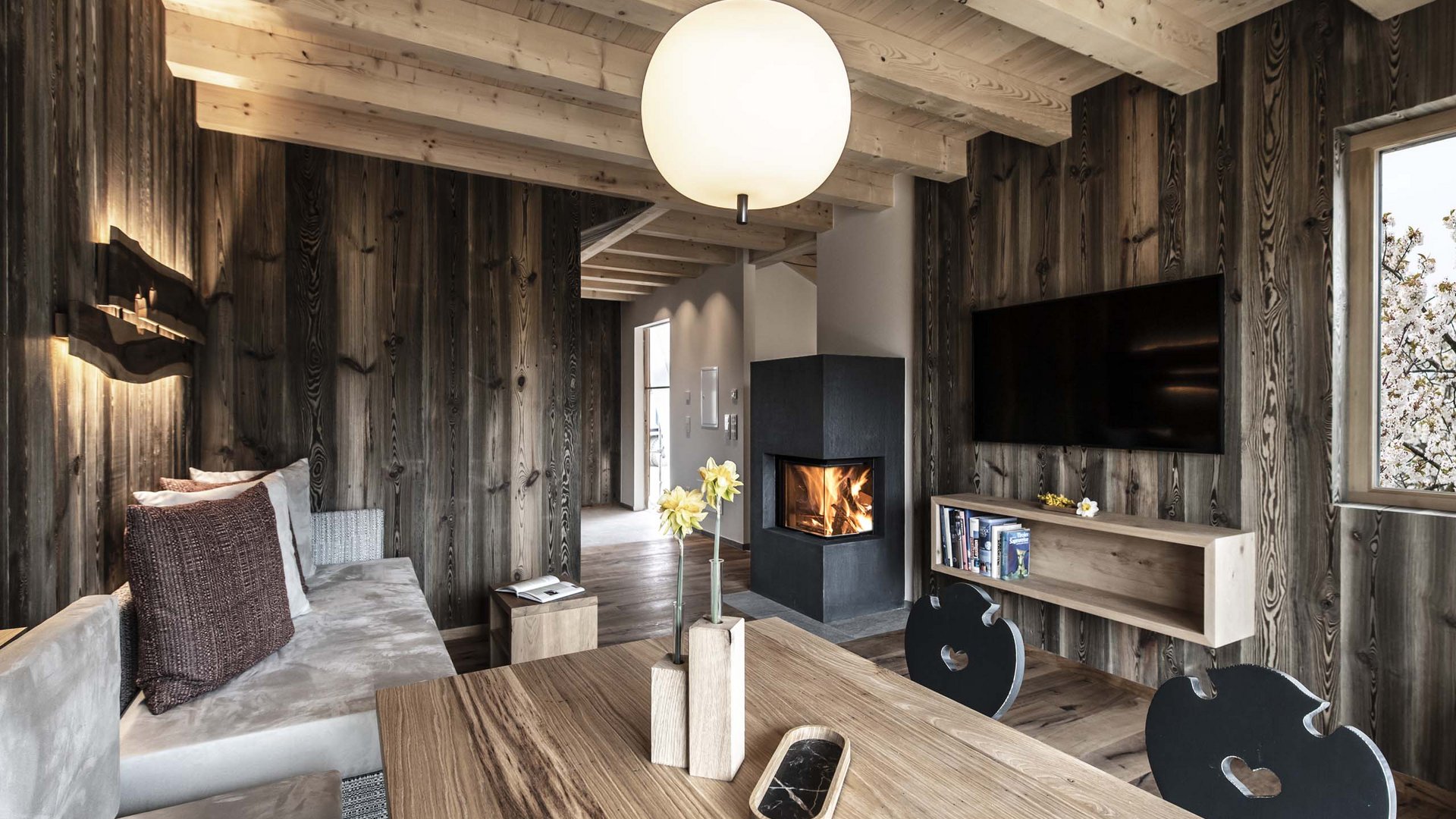 Vacanze in fattoria? Kessler’s Mountain Lodge! Soggiorno accogliente con pareti in legno, camino e televisore moderno