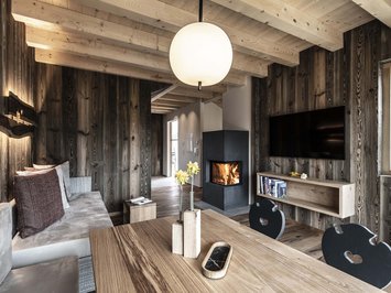 Chalet with a sauna and so much more: Kessler’s Cozy living room with wood paneling, fireplace, and modern TV