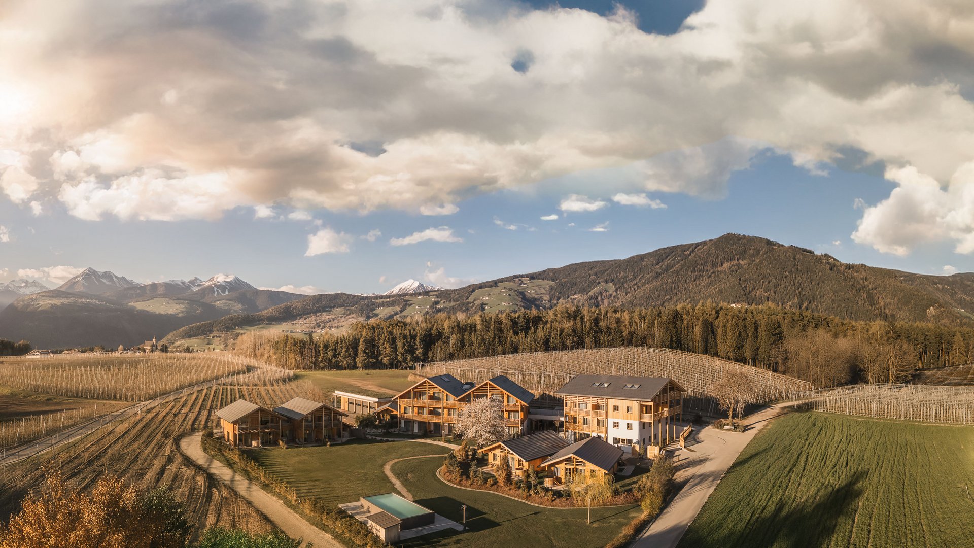 Bauernhof mit Häusern in einem Tal mit Bergen und Wäldern bei Sonnenuntergang