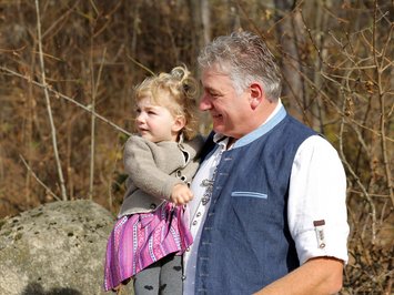 The hosts of your chalets near Brixen Older man holding young girl outdoors in front of autumn forest