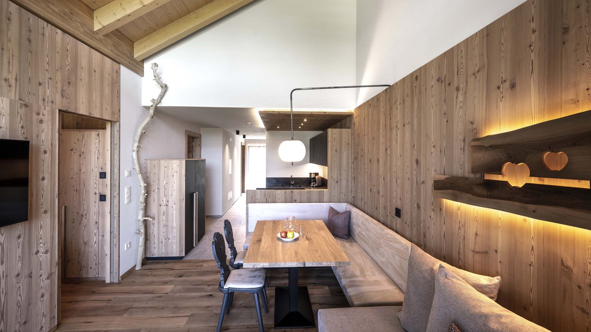 Holiday in Natz-Schabs? Kessler’s Mountain Lodge! Modern dining room with wooden furniture and integrated kitchen corner