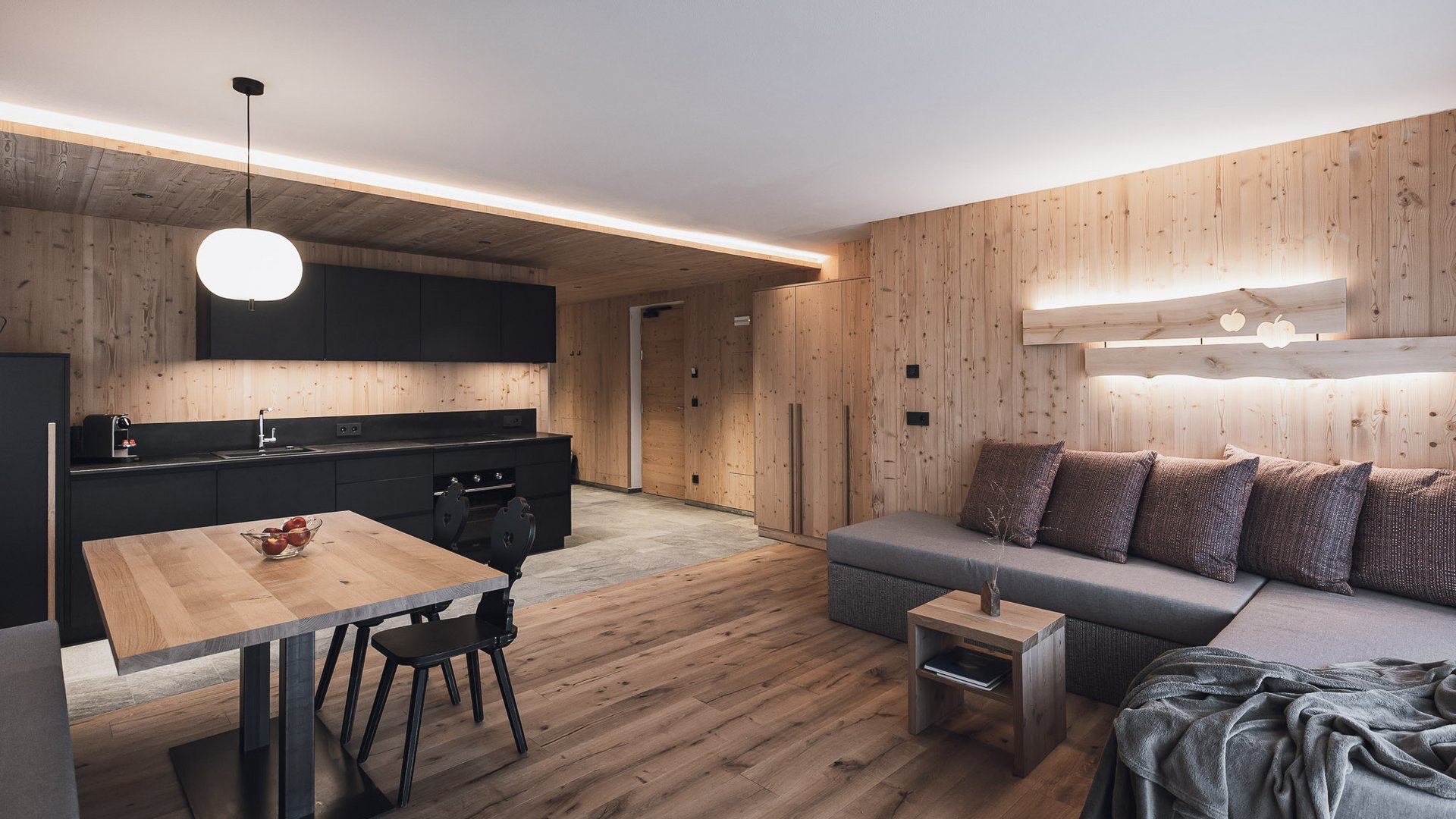 Urlaub in Natz-Schabs? Kessler’s Mountain Lodge! Modernes Wohnzimmer mit offener Küche und Holzwänden