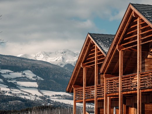 Kessler’s Mountain Lodge: Auszeichnungen Holzhäuser mit Balkonen vor einem verschneiten Bergpanorama