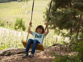 Ferienwohnung in Natz mit dem gewissen Etwas Lachendes Kind schaukelt auf Holzschaukel im Wald