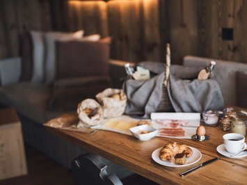 Vacanze in fattoria? Kessler’s Mountain Lodge! Colazione accogliente con croissant, caffè e vari condimenti su tavolo di legno