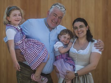 The hosts of your chalets near Brixen Happy family in traditional clothing in front of wooden wall